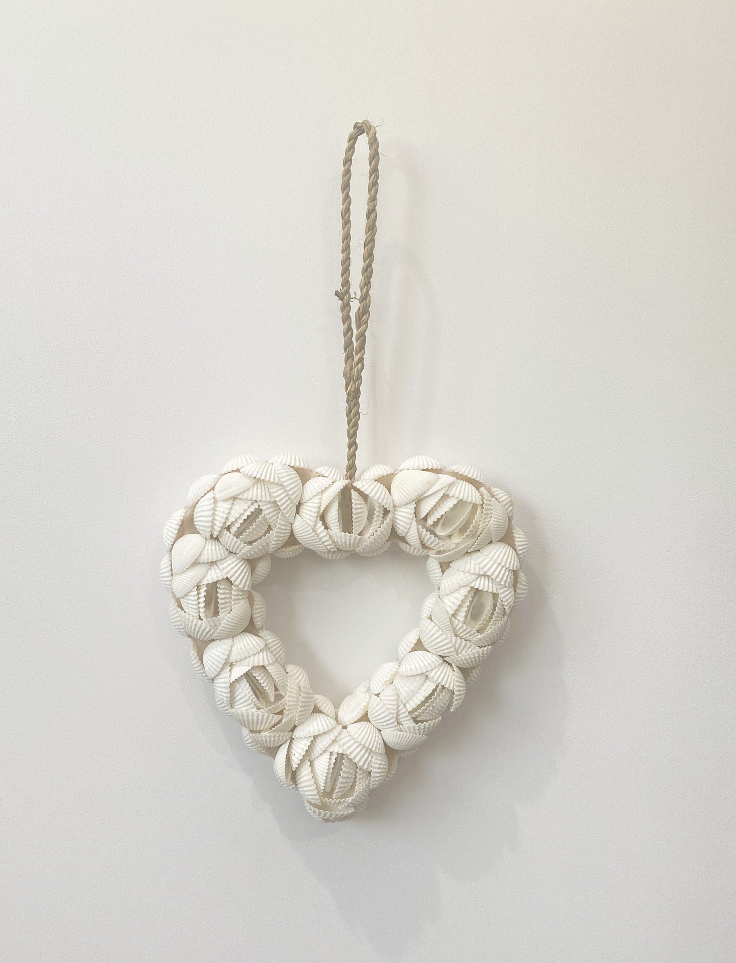 Heart-shape shell flower design decorative wall art pendant made of knotted fabric on a white background