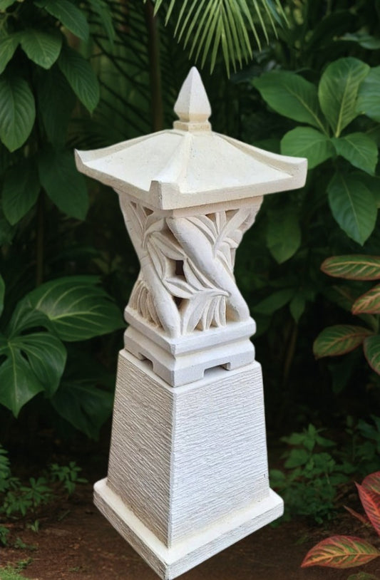 Decorative balinese garden lantern with intricate carvings against a green leafy background