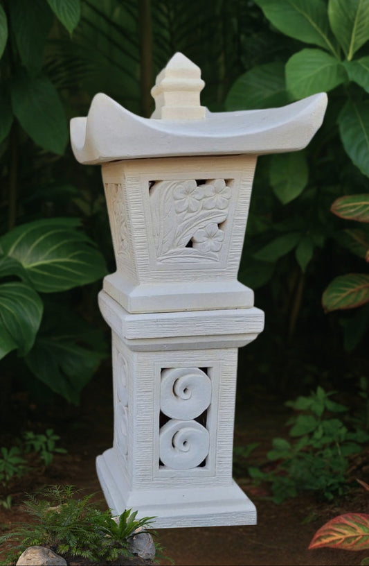 Decorative balinese white concrete garden lantern with intricate carvings against a natural background