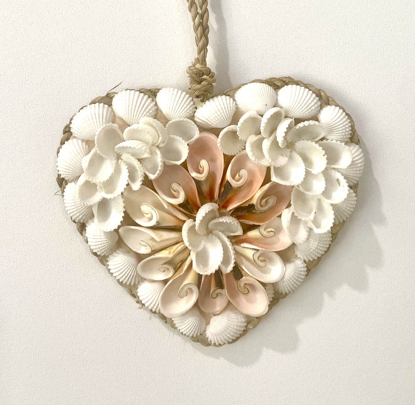 Heart-shaped decorative pendant made of seashells on a white background