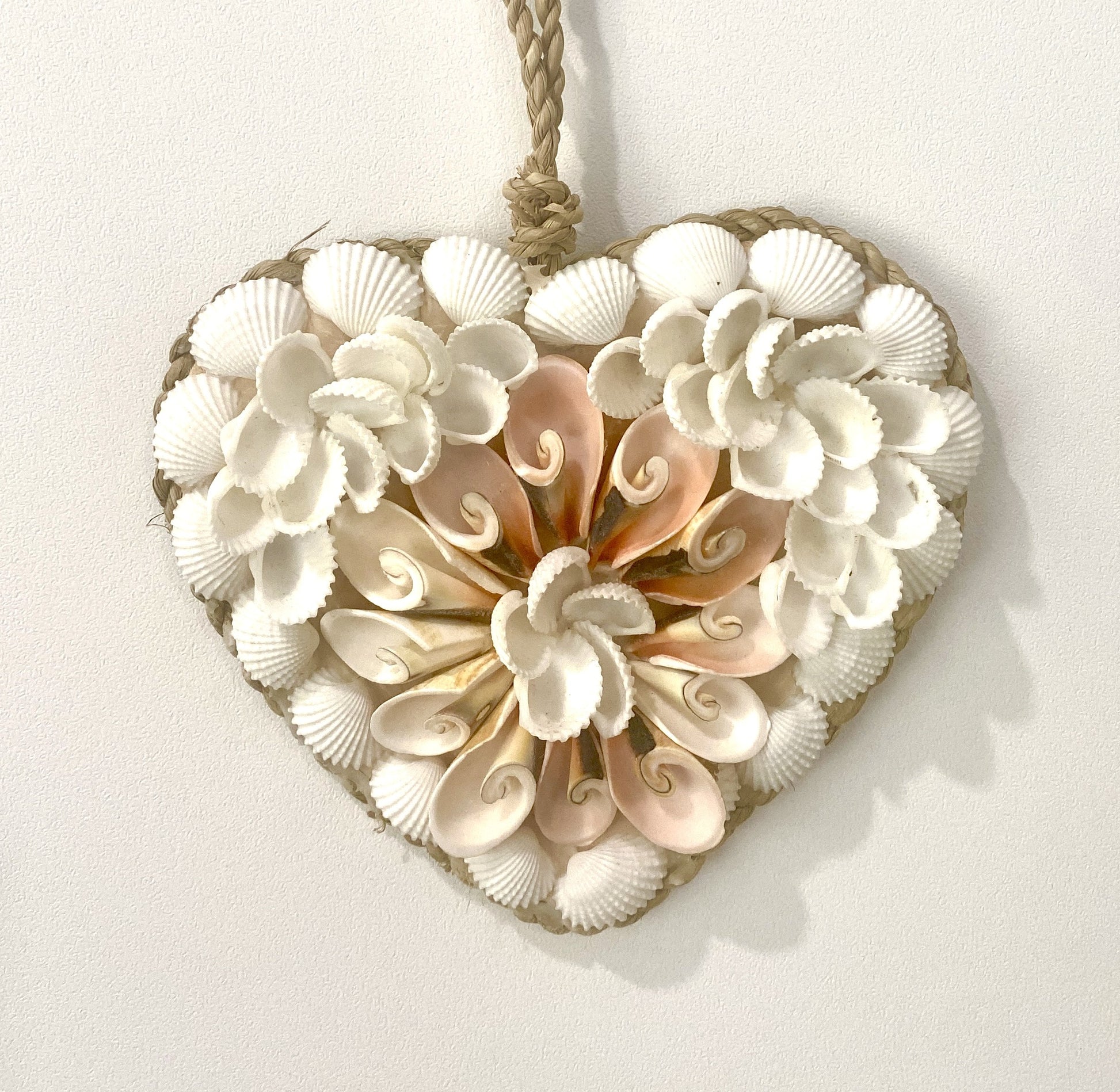 Heart-shaped decorative pendant made of seashells on a white background