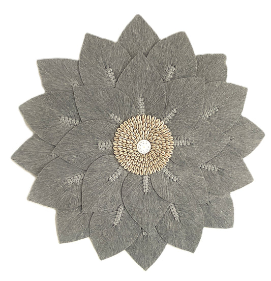 Decorative wall art with a grey macrame flower-like design and cowrie shell center on a white background