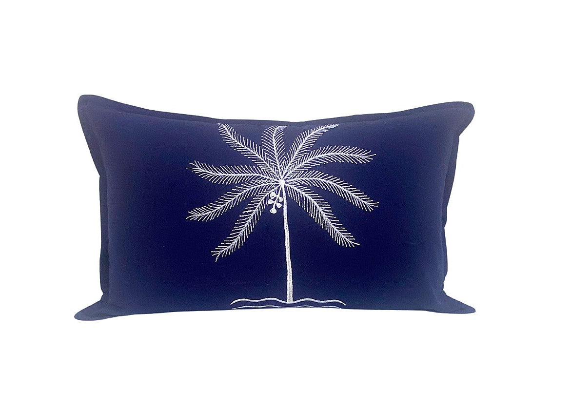 Navy blue pillow with white palm tree design on a white background