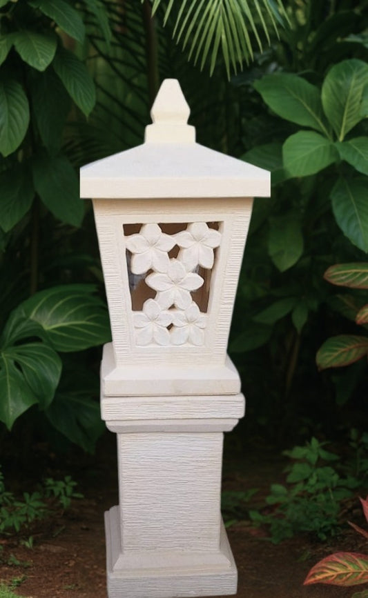 Decorative white balinese lantern with intricate carved frangipani patterns against a natural background